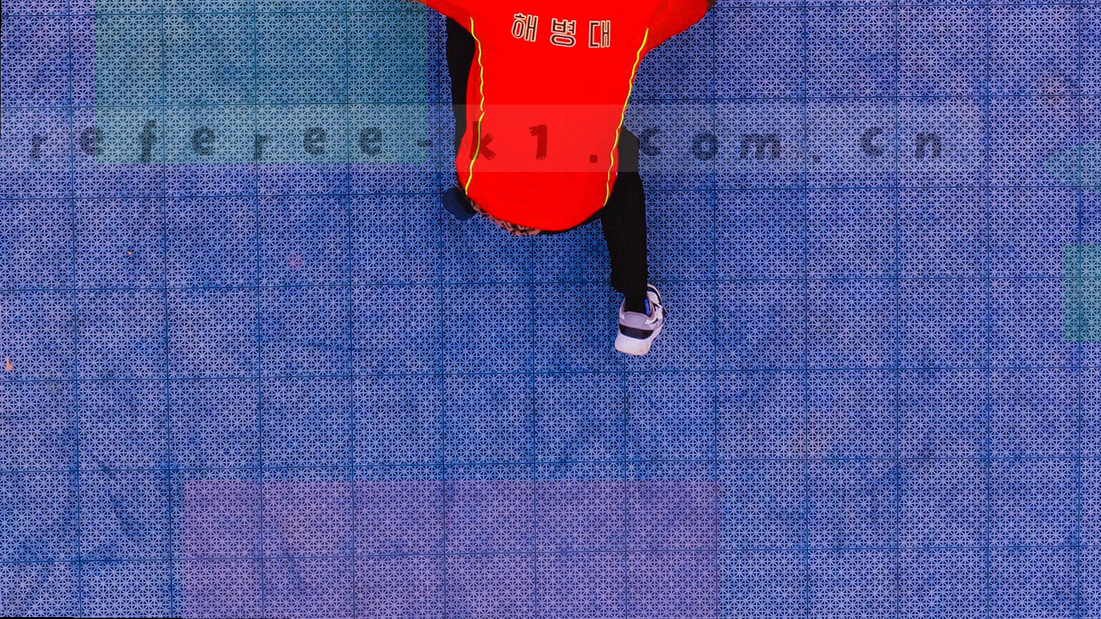 夜间球场俯拍，灯光在草皮上形成青绿与暖黄反光，看台处于暗部